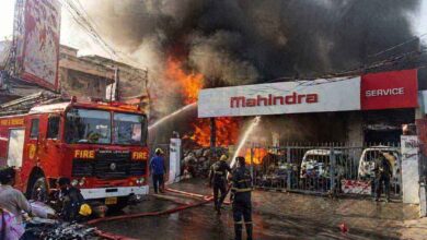 Firefighters controlling massive blaze at Mahindra service center in Amberpet with thick smoke and burning vehicles