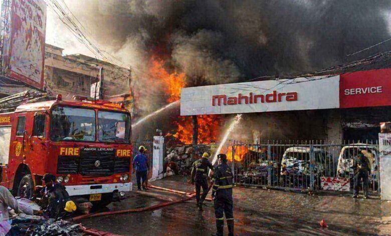 Firefighters controlling massive blaze at Mahindra service center in Amberpet with thick smoke and burning vehicles