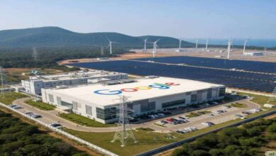 Aerial view of Google data center building with solar panels and wind turbines in a green landscape