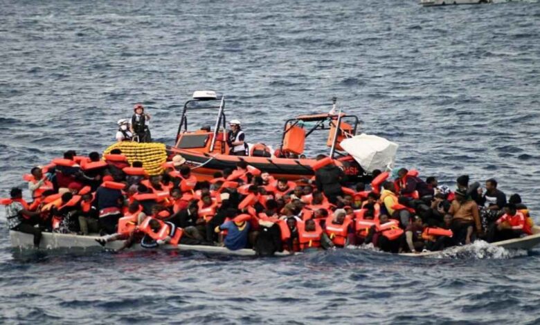 Overcrowded migrant boat at sea with people wearing life jackets as rescue team approaches in a realistic ocean setting