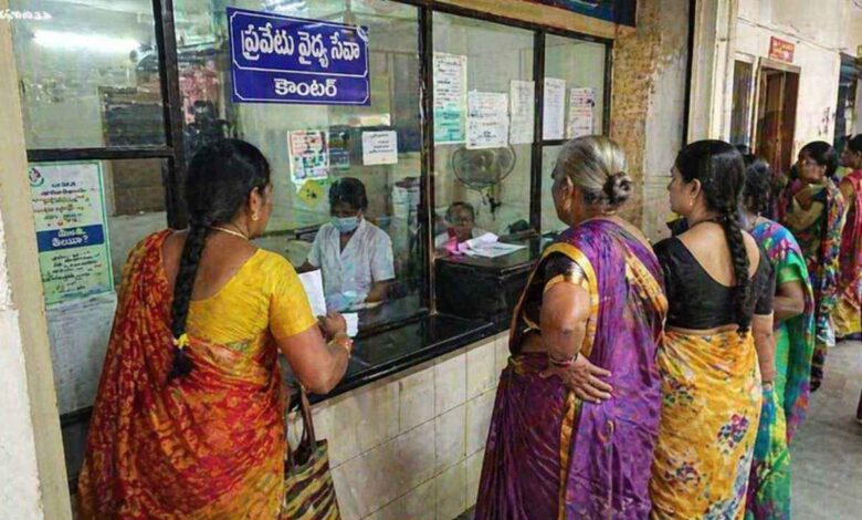 Patients standing in queue at a hospital service counter under NTR Vaidya Seva scheme interacting with staff behind a glass partition