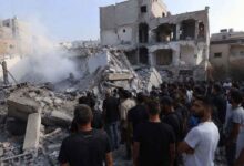People standing near damaged buildings and debris in South Lebanon following airstrikes and conflict related destruction