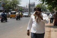 People walking on a busy Telangana road during extreme heatwave conditions under strong summer sunlight.