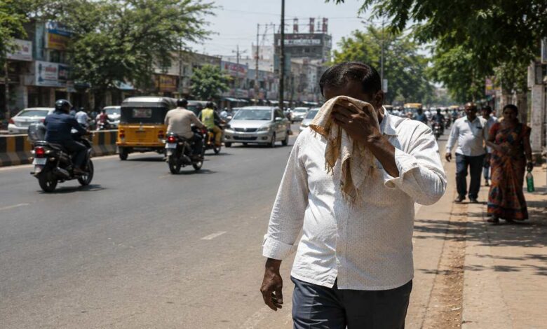 People walking on a busy Telangana road during extreme heatwave conditions under strong summer sunlight.
